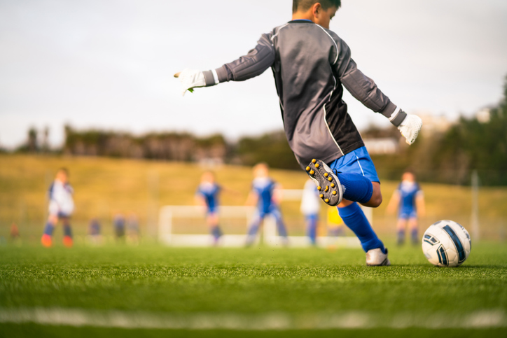 Kid playing soccer in local park.